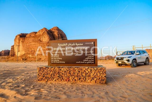 AlUla, Saudi Arabia,Jan 5, 2025: Sharaan Nature Reserve welcome sign in desert, outlining rules for visitors, with a white SUV parked nearby and