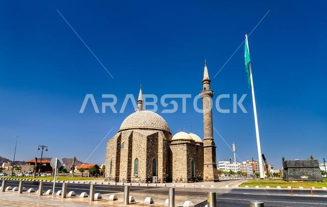 Exterior view of the historic Al Anbariya Mosque with its unique stone dome and minaret under a clear sky in Madinah, Saudi Arabia