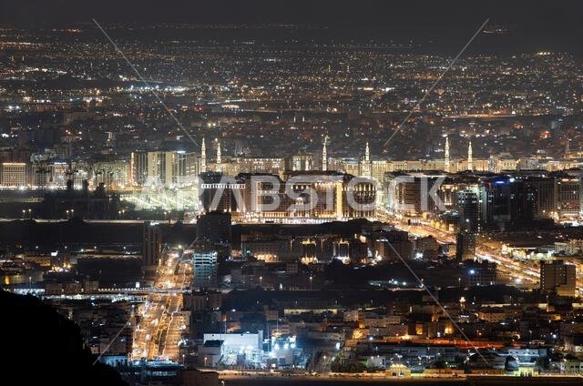 منظر بانورامي ليلي مرتفع لمدينة المدينة المنورة من جبل أحد، يضم المسجد النبوي وأضواء الشوارع الحضرية في المملكة العربية السعودية.