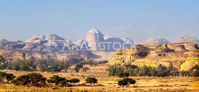 المناظر الطبيعية الصحراوية الخلابة لجبل إثلب والتكوينات الصخرية القديمة في الحِجر، العلا، المملكة العربية السعودية، والتي تتميز بجبال من الحجر الرملي وتكوينات صخرية متناثرة.