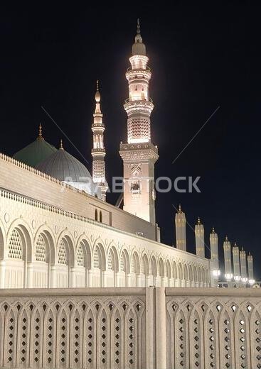 Vertical Night Shot For The Green Dome and Minarets of Al-Masjid An-Nabawi Surounded By An Islamic Architecture Wall, Medina, Saudi Arabia.