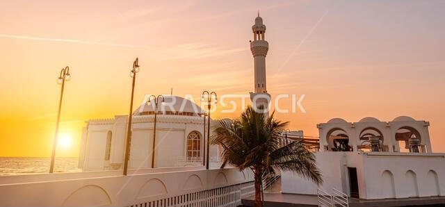 sun goes down on Al Rahmah Mosque on Jeddah Waterfront with JYC Jeddah Yacht Club building, on the Red Sea coast of Saudi Arabia, at sunset