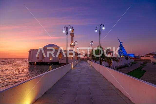 Majestic golden Jeddah's corniche at sunset, with the Al Rahmah Mosque glowing in the background in Saudi Arabia Majestic golden Jeddah's corniche at sunset, with the Al Rahmah Mosque glowing in the background in Saudi Arabia
