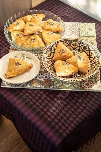 سمبوسة مصنوعة من عجينة الباف باستري. فطيرة مثلثة الشكل محشوة باللحم، ومزينة ببذور السمسم. صورة من أعلى الطبق سمبوسة مصنوعة من عجينة الباف باستري. فطيرة مثلثة الشكل محشوة باللحم، ومزينة ببذور السمسم. صورة من أعلى الطبق