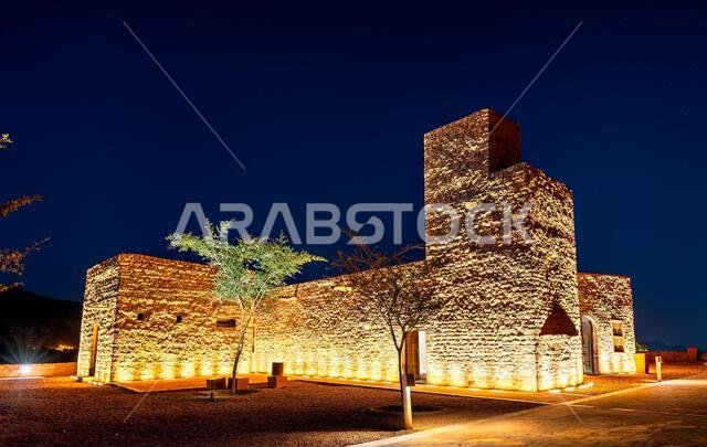The historic AlUla Fort illuminated by warm lights under a starry night sky in the Al Madinah Province of Saudi Arabia.