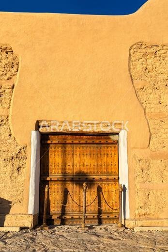 Traditional wooden door and mud brick wall at the historic At-Turaif World Heritage Site in Diriyah, Saudi Arabia.