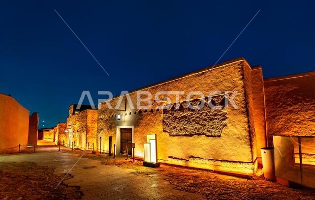 Beautifully illuminated traditional Najdi mud brick architecture at the historic At-Turaif district in Diriyah, Saudi Arabia at night.
