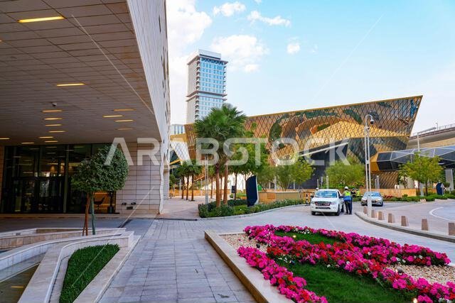 مدخل مبنى إداري مزين بأحواض زهور في مركز الملك عبد الله المالي (KAFD) في الرياض، المملكة العربية السعودية