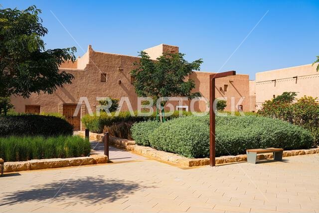 ساحة عامة في زقاق القرعة، تضم حدائق خضراء ومبانٍ تقليدية من الطوب اللبن في حي الضو التاريخي، الرياض، المملكة العربية السعودية