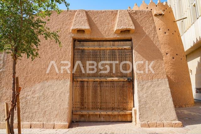 بوابة خشبية منحوتة تقليدية وجدار من الطوب اللبن في حي الضو التاريخي، الرياض، المملكة العربية السعودية بوابة خشبية منحوتة تقليدية وجدار من الطوب اللبن في حي الضو التاريخي، الرياض، المملكة العربية السعودية