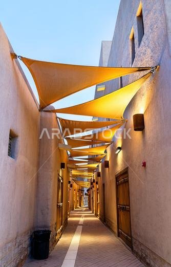 A narrow heritage street with traditional Najdi architecture and sun shades in the Al Gadimah historic district of Riyadh, Saudi Arabia. A narrow heritage street with traditional Najdi architecture and sun shades in the Al Gadimah historic district of Riyadh, Saudi Arabia.