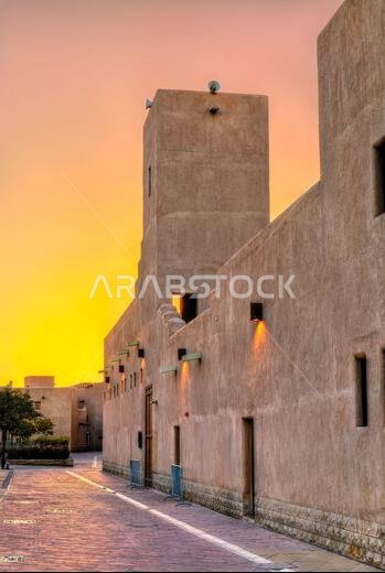 Historic clay wall and tower of Hilla Mosque in the Al Doho district of Riyadh, Saudi Arabia, during a golden sunset