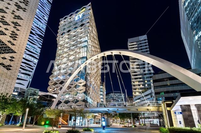 Riyadh, Saudi Arabia - February 19, 2026: Modern pedestrian arch bridge and illuminated office skyscrapers in King Abdullah Financial District at night. Riyadh, Saudi Arabia - February 19, 2026: Modern pedestrian arch bridge and illuminated office skyscrapers in King Abdullah Financial District at night.