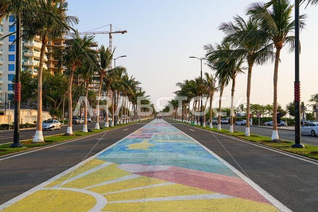 Symmetrical view of a colorful painted pedestrian walkway lined with palm trees at Jeddah New Corniche, Saudi Arabia
