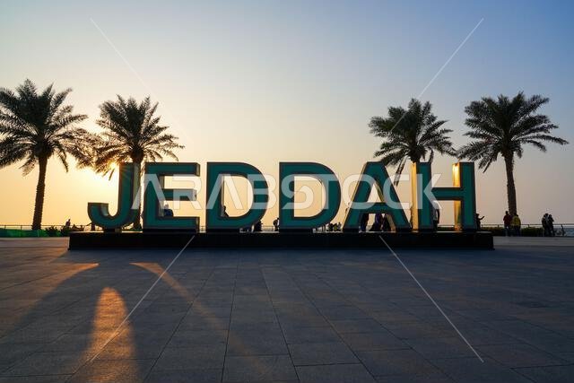 Monumental Jeddah city sign and palm trees at sunset on the Jeddah New Corniche waterfront in Saudi Arabia