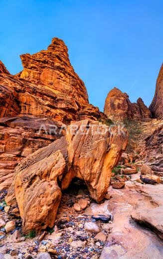 Ancient carved inscriptions on towering red sandstone cliffs at Jabal Ikmah in AlUla, Saudi Arabia
