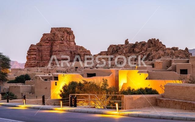 منظر للعمارة التقليدية المبنية من الطوب اللبن والحصن التاريخي لمدينة العلا القديمة مضاءة عند الغسق في المملكة العربية السعودية.