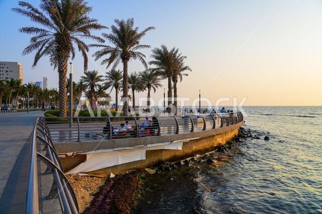 أشخاص يسترخون على رصيف الواجهة البحرية المنحني والمتنزه في كورنيش جدة الجديد، المملكة العربية السعودية