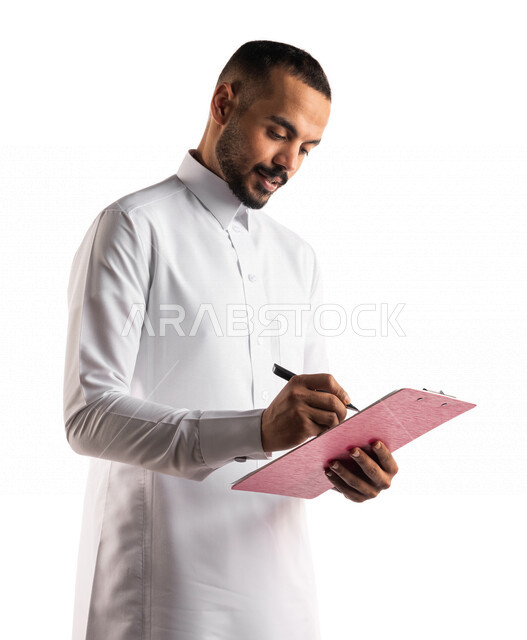 بورتريه لرجل عربي خليجي سعودي يقوم بتدوين الملاحظات على اوراق و ملفات خاصة بالعمل ، التخطيط للعمل ، توقيع عقد عمل ، تدوين نتائج الاجتماع ، اعداد تقارير ومهام العمل ، دراسة جدوى الاعمال ، خلفية بيضاء