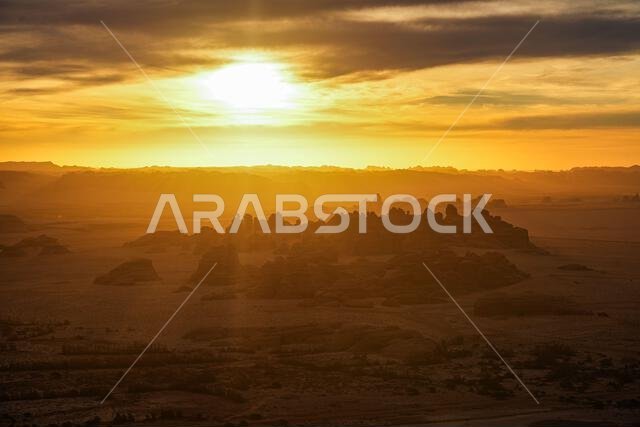 Sunbeams over backlit sandstone rock formations at sunrise in the ancient site of Hegra, AlUla