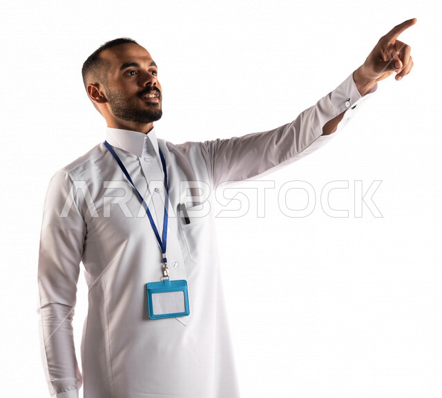 Portrait of a Saudi Arabian Gulf man wearing a white cut-out identification card and pointing with his index finger at something, specifying a goal, finger movement and gestures, giving seminars and lectures, supervising and following up, white background