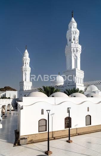 The bright white minarets and domes of the historic Masjid al Qiblatayn mosque under a clear blue sky in Madinah, Saudi Arabia