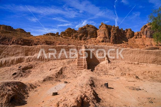Ancient mudbrick ruins against red sandstone mountains in the historical heritage oasis of AlUla, Saudi Arabia