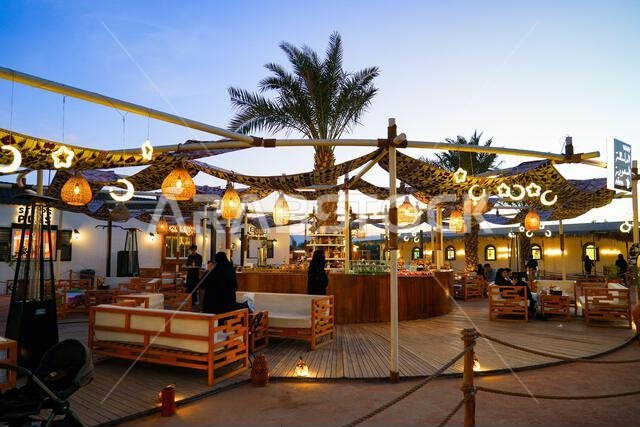 Traditional open-air cafe decorated with illuminated crescent moons and stars lamps at dusk in Madinah, Saudi Arabia