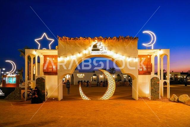 Monumental entrance gate of Maqsid Quba decorated with neon crescent moons and stars at blue hour in Madinah, Saudi Arabia