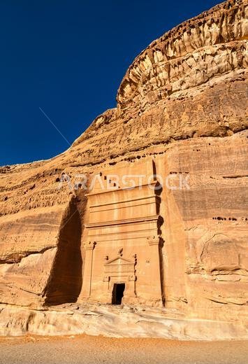 مقبرة نبطية مهيبة منحوتة مباشرة في جبال الحجر الرملي الأحمر في الحِجر في العلا، المملكة العربية السعودية، وهو موقع تراث عالمي لليونسكو معروف بهندسته المعمارية النبطية القديمة.