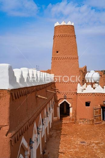 Mud brick minaret of Al-Faylaqia Mosque with white crenellations in Ushaiqer, Saudi Arabia