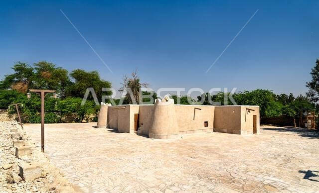 منظر خارجي لمسجد جواتة التاريخي المبني بالطوب اللبن التقليدي تحت سماء زرقاء صافية في الأحساء، المملكة العربية السعودية.