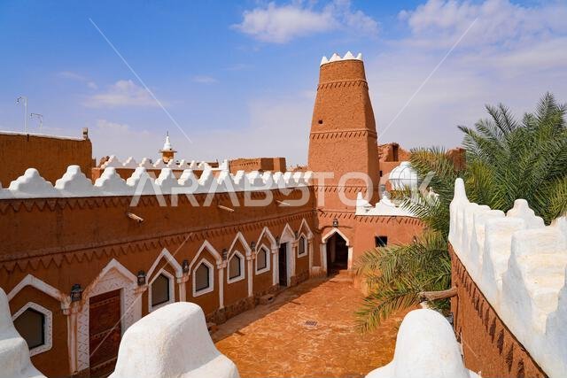 فناء مسجد الفيلقية التقليدي المبني من الطوب اللبن مع الشرفات البيضاء في أوشيقر، المملكة العربية السعودية