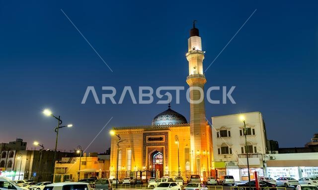 Beautifully illuminated traditional Bu Khamseen Mosque with a tall minaret and colorful dome in Al Hofuf, Al Ahsa, Saudi Arabia at night