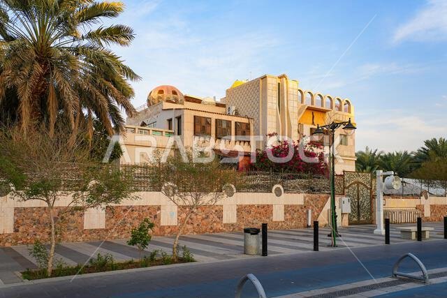A traditional luxury villa with wooden moucharabieh windows and pink bougainvillea flowers along Quba Avenue in Madinah, Saudi Arabia