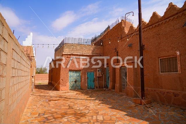 Traditional mud brick houses with turquoise doors and string lights in the heritage village of Ushaiqer, Saudi Arabia