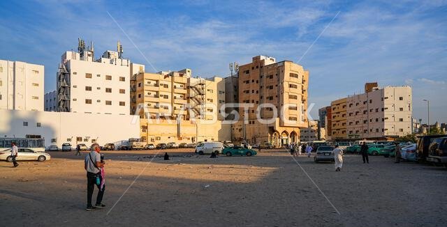 A dusty dirt parking lot surrounded by apartment buildings in Madinah, Saudi Arabia
