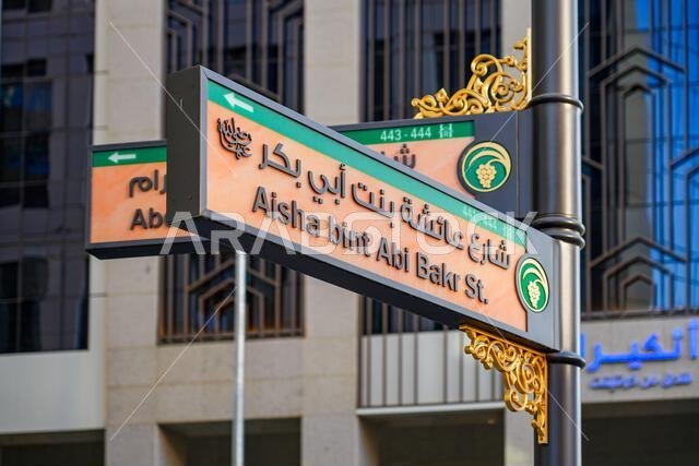 Bilingual street sign for Aisha bint Abi Bakr Street with gold arabesque decorations in Madinah, Saudi Arabia