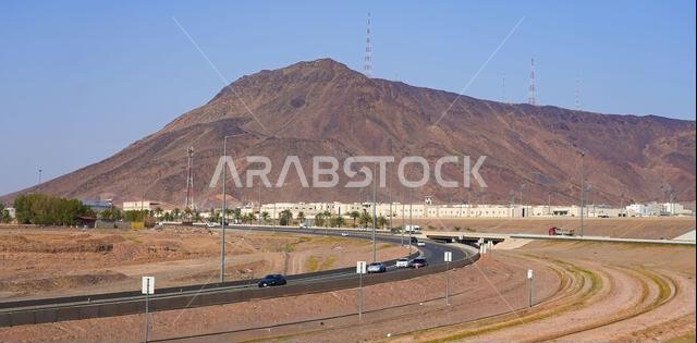 The majestic Jabal Ayr mountain and its historic fortress surroundings behind a highway network in Madinah, Saudi Arabia