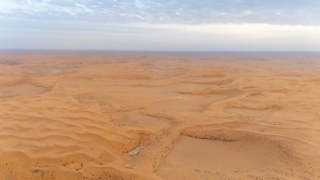 منظر جوي للكثبان الرملية الصحراوية البرتقالية تحت سماء غائمة