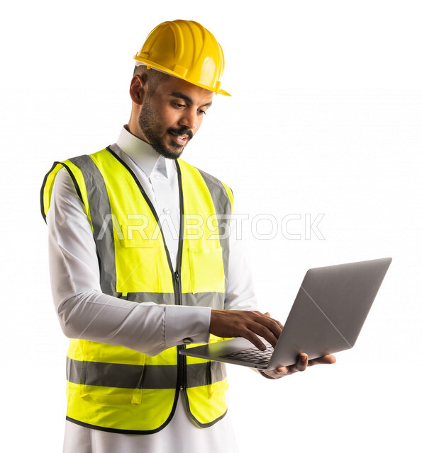 Portrait of a Saudi Arabian Gulf engineer wearing a work helmet and protective jacket using a laptop computer to accomplish and track engineering tasks, engineering professions and jobs, the concept of architecture, a professional architect
