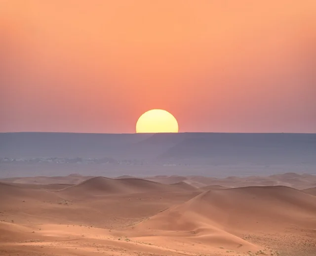 غروب الشمس الذهبي فوق الكثبان الرملية في صحراء النفود