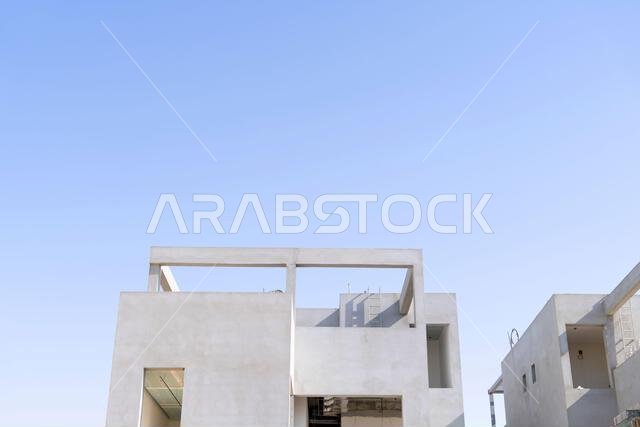 منزل جديد قيد الإنشاء في الرياض، المملكة العربية السعودية، يظهر جدراناً إسمنتية، وهيكلاً غير مكتمل، ومراحل بناء مبكرة لعقار سكني.