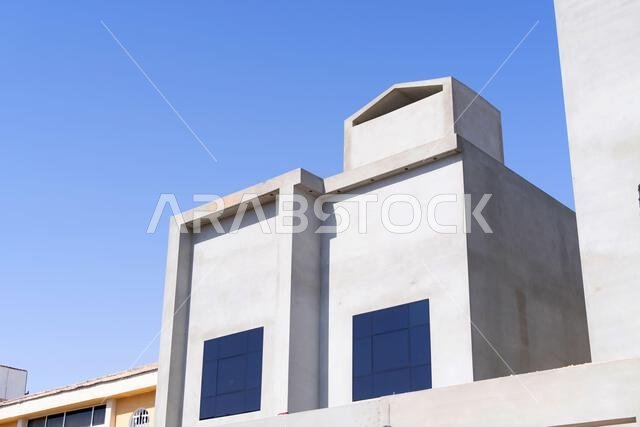 منزل جديد قيد الإنشاء في الرياض، المملكة العربية السعودية، يظهر جدراناً إسمنتية، وهيكلاً غير مكتمل، ومراحل بناء مبكرة لعقار سكني.