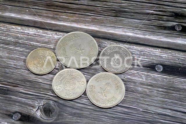 عملات سعودية متعددة بقيم مختلفة، طراز قديم، سعر صرف الريال السعودي، والوضع الاقتصادي للمملكة العربية السعودية، السعودية القديمة