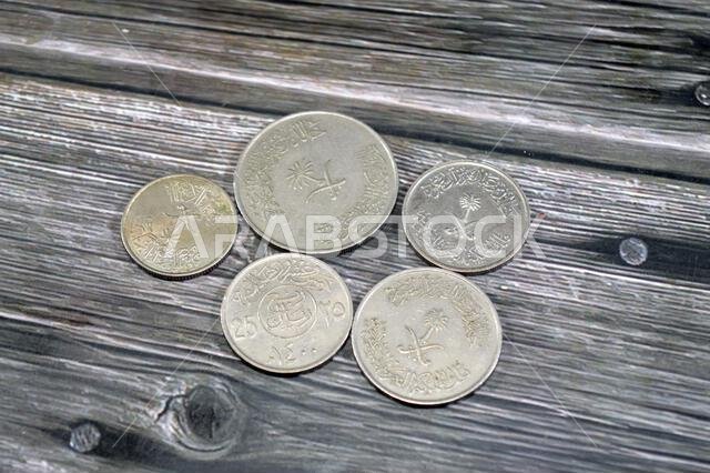 عملات سعودية متعددة بقيم مختلفة، طراز قديم، سعر صرف الريال السعودي، والوضع الاقتصادي للمملكة العربية السعودية، السعودية القديمة