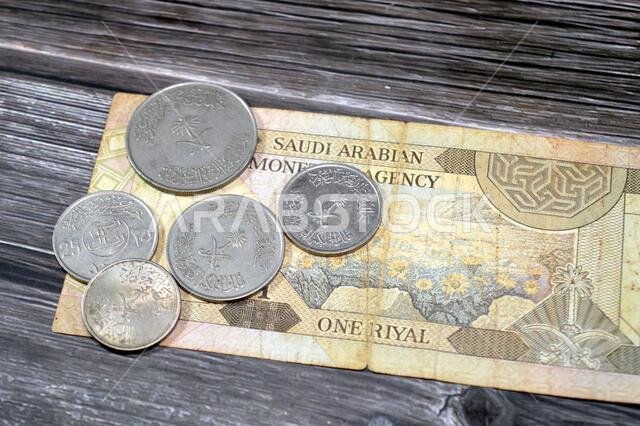 Old Saudi Arabian coins of different values on Saudi Arabia banknote bill, one 1 Riyal SAR, vintage retro, Riyals money exchange rate and economy stat