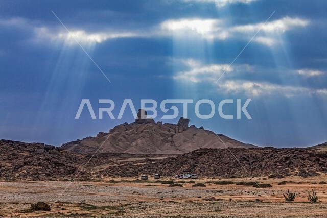 منظر بعيد للسياح وسيارات الدفع الرباعي المتوقفة بجانب الصخور في الصحراء، المملكة العربية السعودية