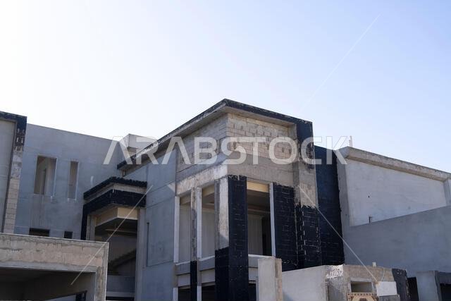 New house under construction in Riyadh, Saudi Arabia, showing cement walls, unfinished structure, and early building stages of a residential property.