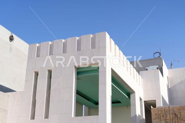منزل جديد قيد الإنشاء في الرياض، المملكة العربية السعودية، يظهر جدراناً إسمنتية، وهيكلاً غير مكتمل، ومراحل بناء مبكرة لعقار سكني. منزل جديد قيد الإنشاء في الرياض، المملكة العربية السعودية، يظهر جدراناً إسمنتية، وهيكلاً غير مكتمل، ومراحل بناء مبكرة لعقار سكني.